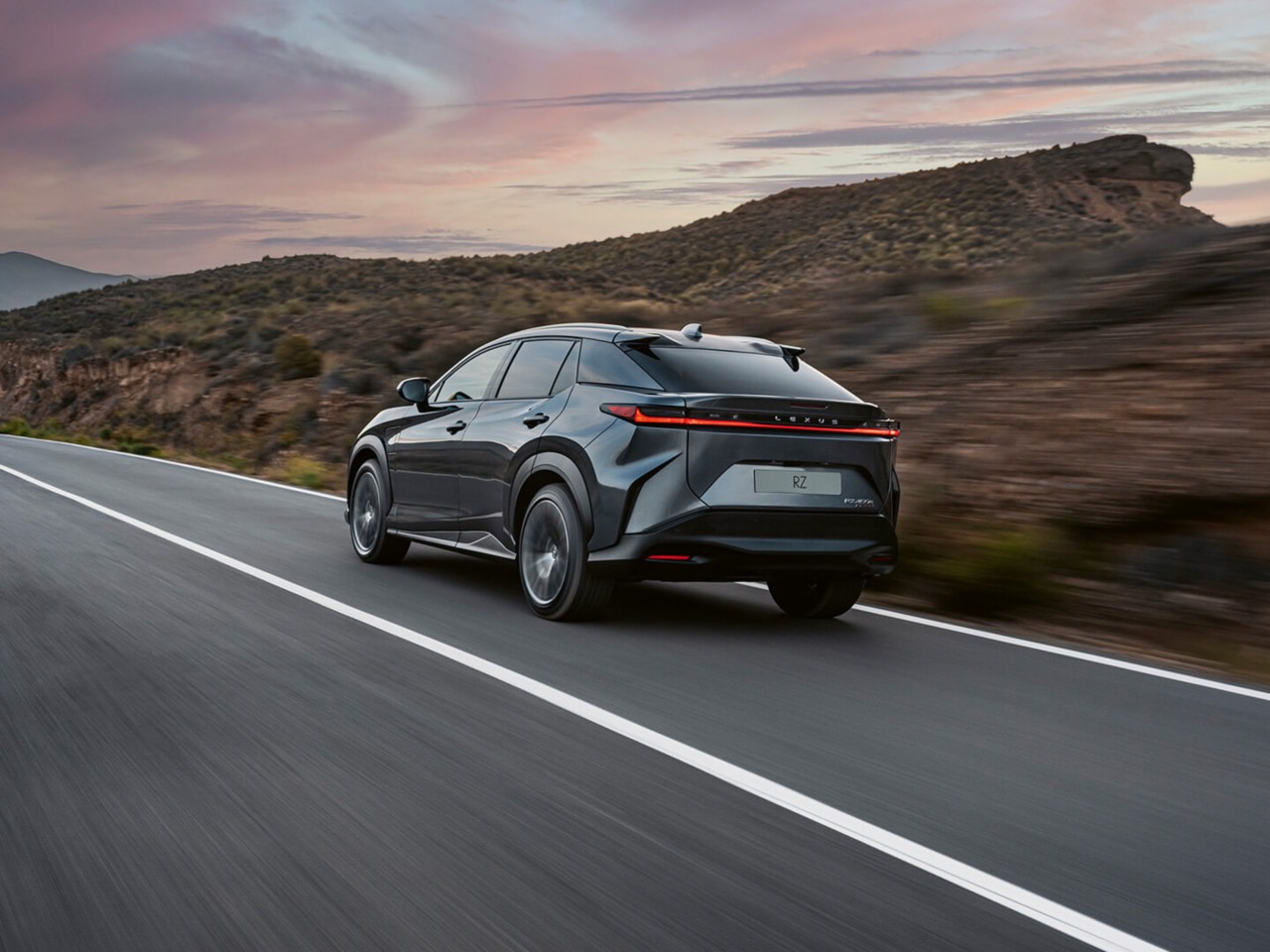 Rear view of the Lexus RZ driving in a rural environment 