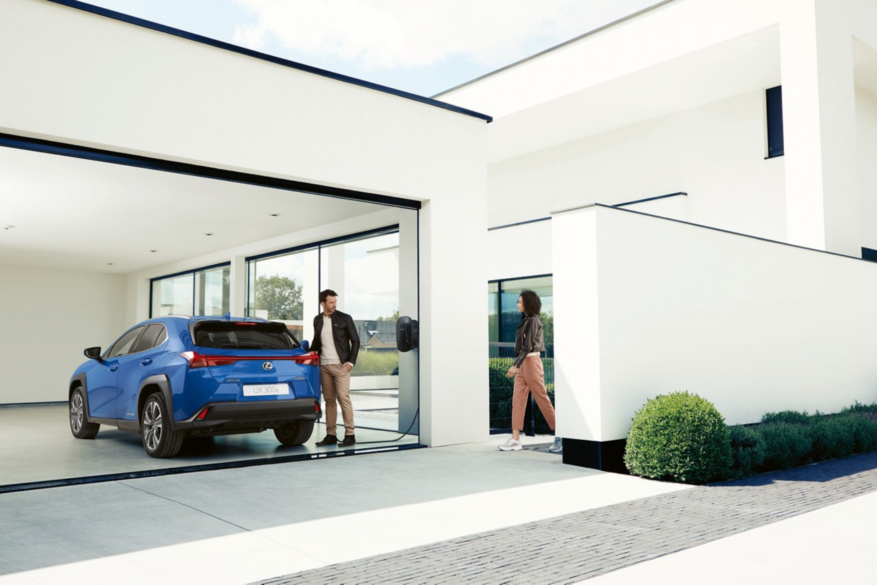 A person standing next to a Lexus on the driveway