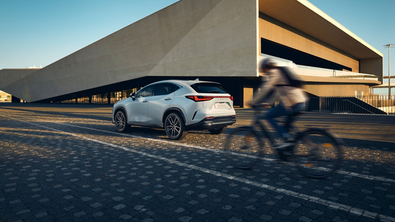 A person cycling past a Lexus NX 