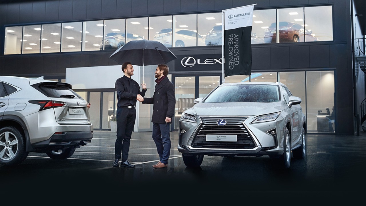 A Lexus dealer and a customer shaking hands outside a Lexus dealership 